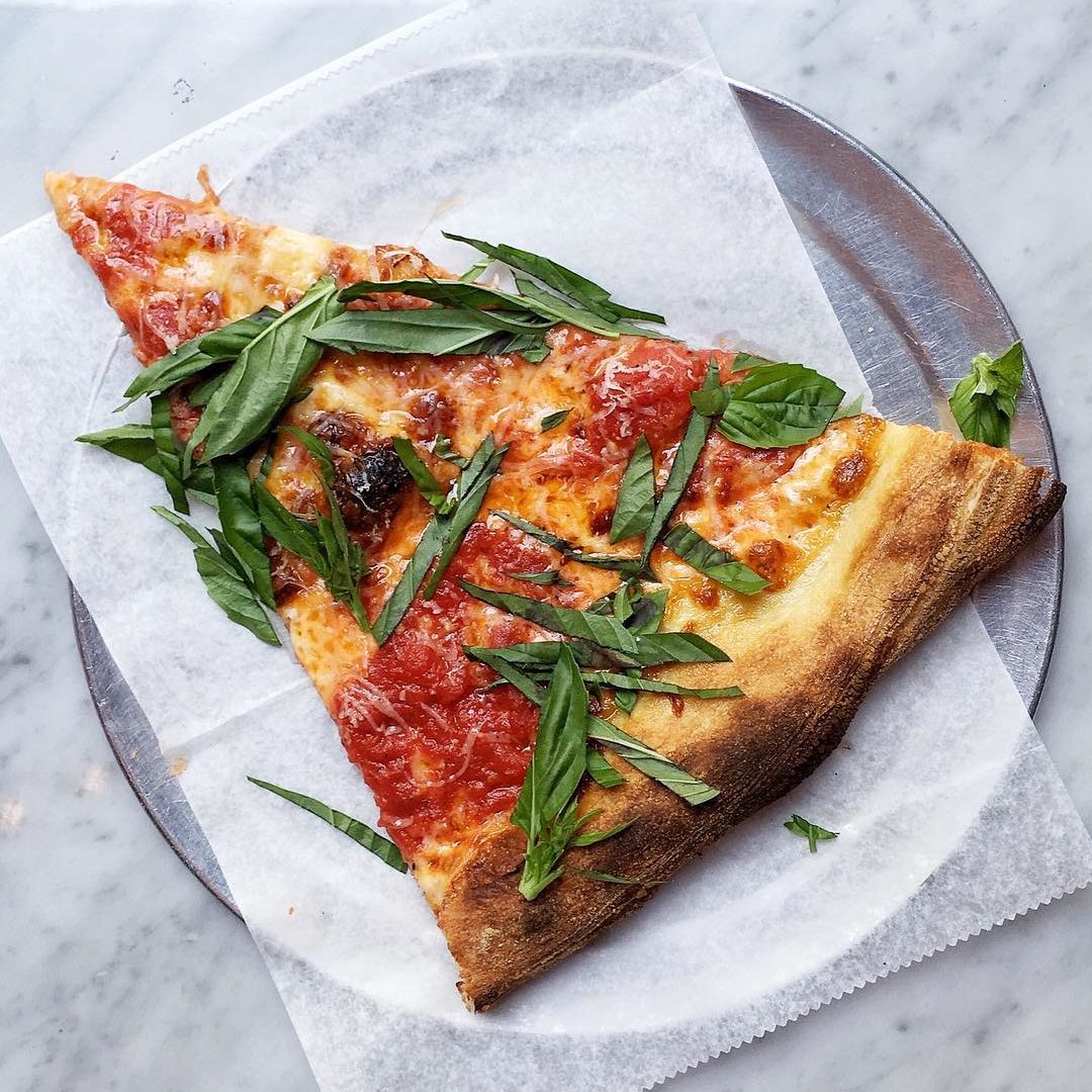 A slice of pizza with chopped basil